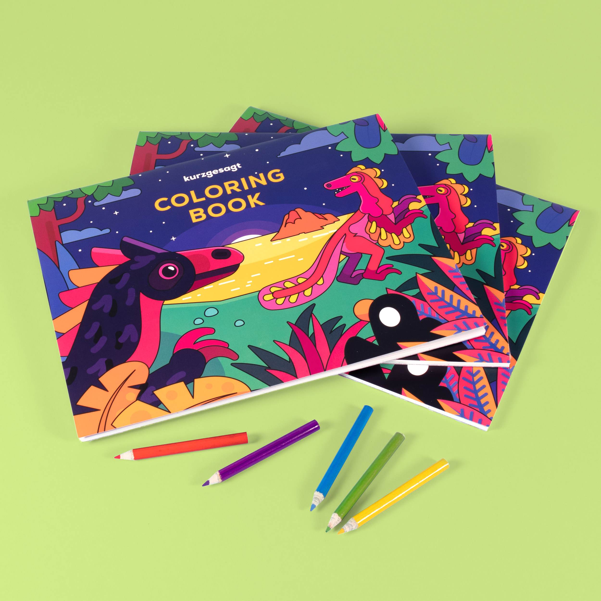 Coloring Book with vibrant animal illustrations, surrounded by colored pencils on green background.